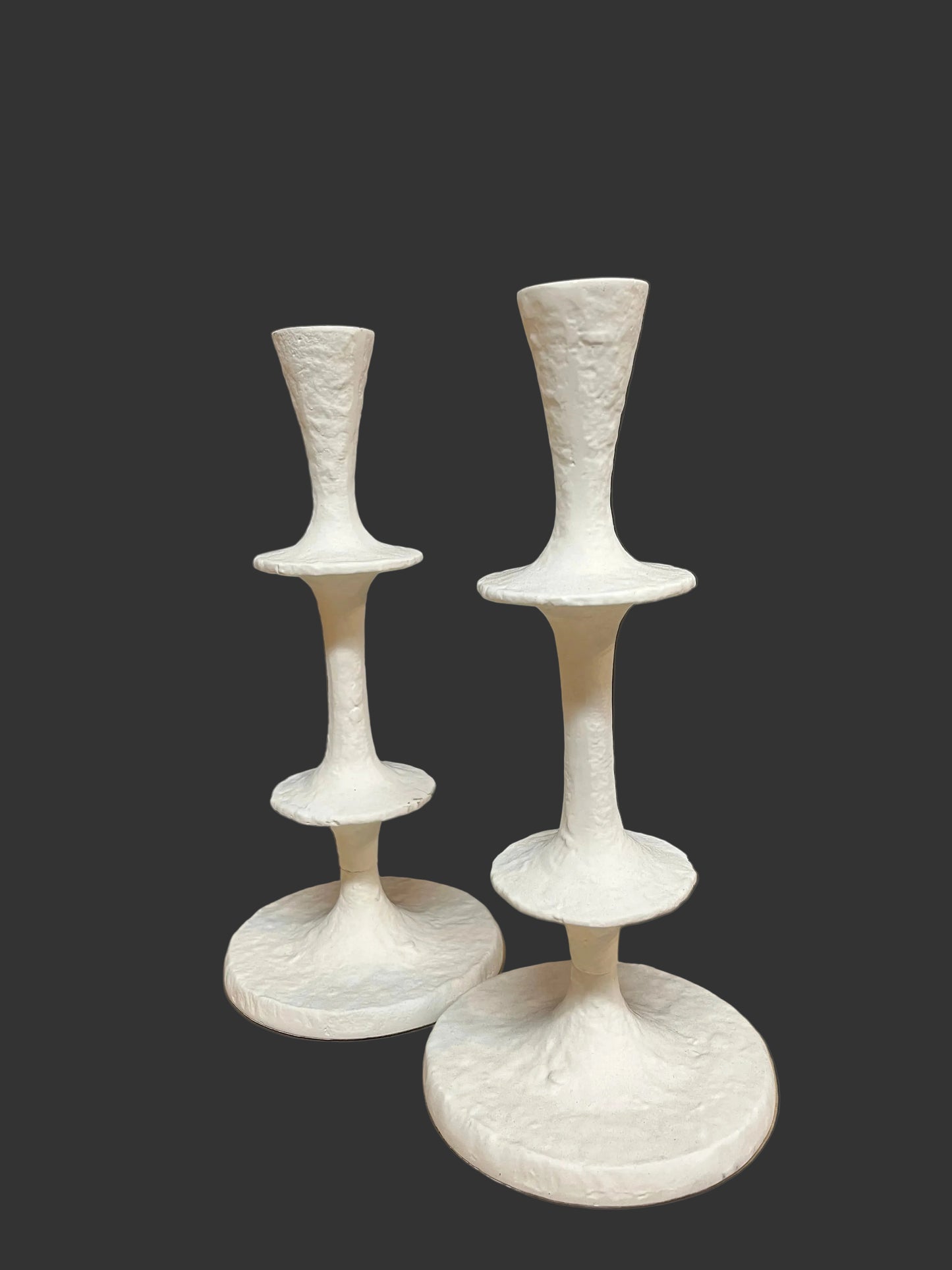 Set of four white ceramic candle holders on a black and beige surface