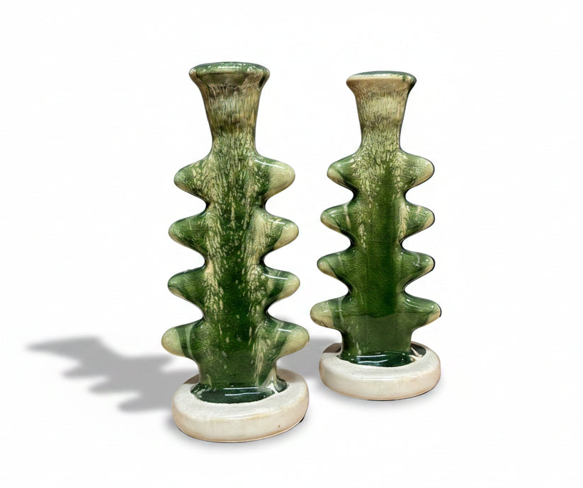 Two green ceramic candle holders on a white background