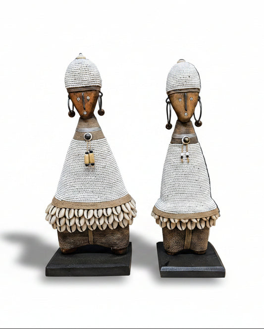 Two decorative statues resembling african ladies on a dark surface.